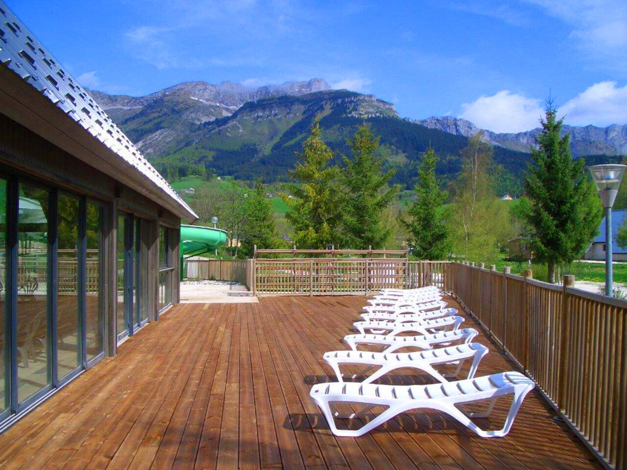 Terraza de madera, tumbonas, tobog�n, monta�as en el camping CAPFUN Oursi�re en Villard de Lans (38).