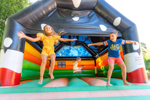 Niños saltando alegremente en un castillo hinchable colorido en el camping CAPFUN Oursière en Villard de Lans (38).