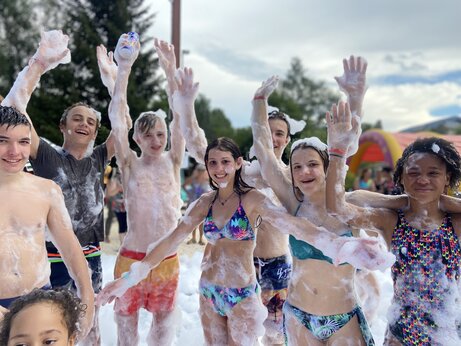 Niños y adolescentes sonrientes disfrutando de una fiesta de espuma en el camping CAPFUN Oursière en Villard de Lans (38).