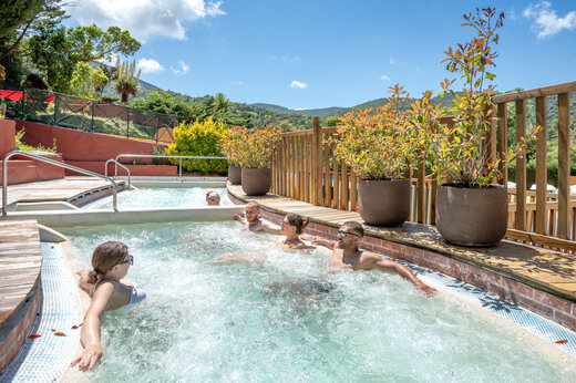 Jacuzzi exterior con burbujas y personas relajándose en camping CAPFUN Pachacaid en La Mole (83).