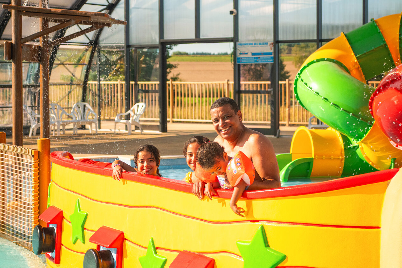 Familia sonriente en estructura de juegos acu�ticos con tobog�n en el camping CAPFUN Pachy en FOSSES LA VILLE.