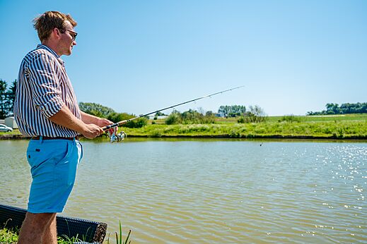 Hombre pescando en un estanque soleado en el camping CAPFUN Pachy en FOSSES LA VILLE.