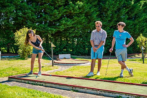 Jóvenes jugando al minigolf en un campo verde en el camping CAPFUN Pachy en FOSSES LA VILLE.