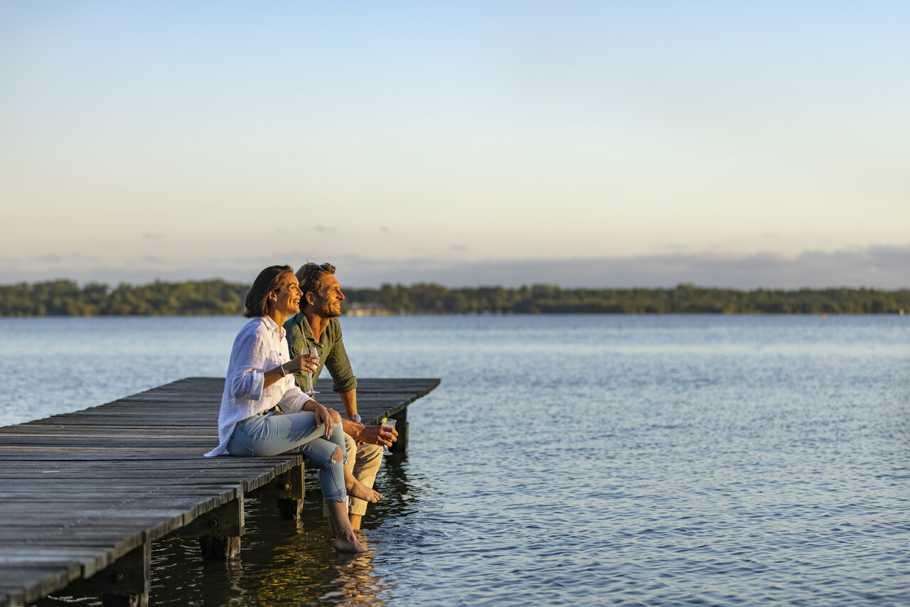 Pareja en muelle, pies en agua en CAPFUN Paillotte en AZUR (40).