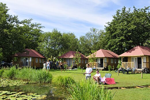 Mobil-homes de madera junto a estanque con pescadores en camping CAPFUN Paillotte en AZUR (40).