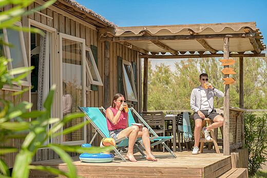 Pareja relajándose en la terraza de un Mobil-home en el camping CLICOCHIC Palmira Beach (34).