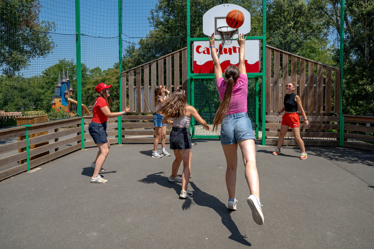 J�venes jugando baloncesto en cancha multideporte en el camping CAPFUN Palombi�re en Sarlat.