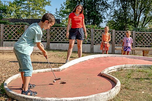 Niño jugando al minigolf en el campo del camping CAPFUN Palombière en SAINT-NATHALENE (24).