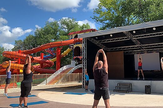 Clase de fitness al aire libre con toboganes acuáticos en el camping CAPFUN Palombière en SAINT-NATHALENE.