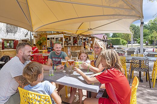 Familia sonriente brindando en el bar del camping CAPFUN Paradis de Bazas (33).