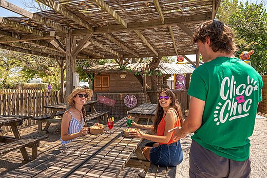 Bar exterior sombreado, mesas de picnic en el camping CLICOCHIC Paradou en Marseillan-Plage.