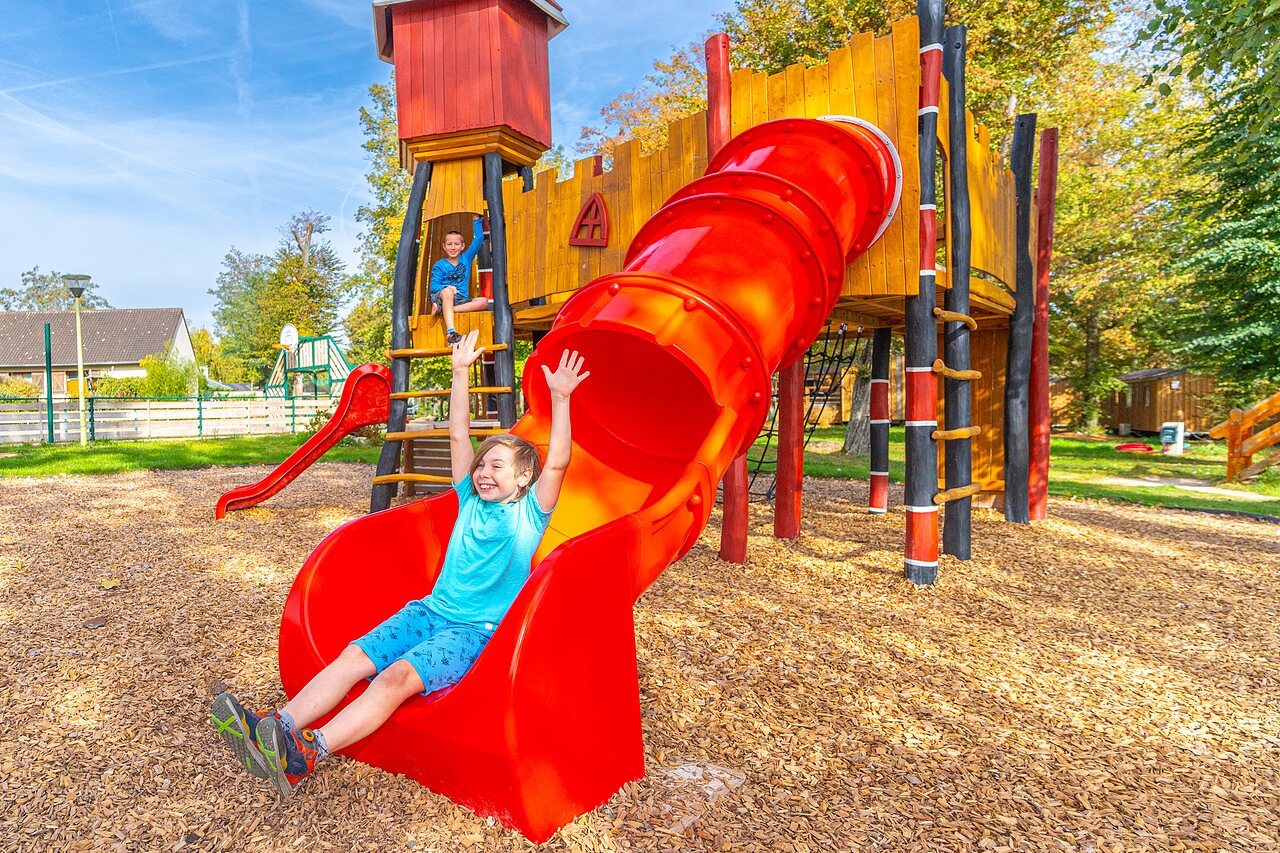 Ni�o sonriendo en tobog�n rojo parque infantil en camping CAPFUN Parc de Paris en Villevaud� (77).