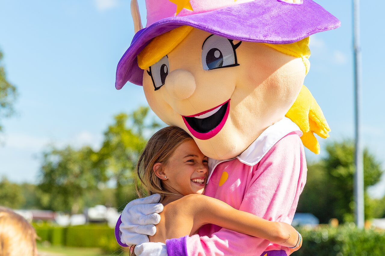Ni�a sonriente abrazando la mascota del camping CAPFUN Parc de Paris en Villevaud� (77).