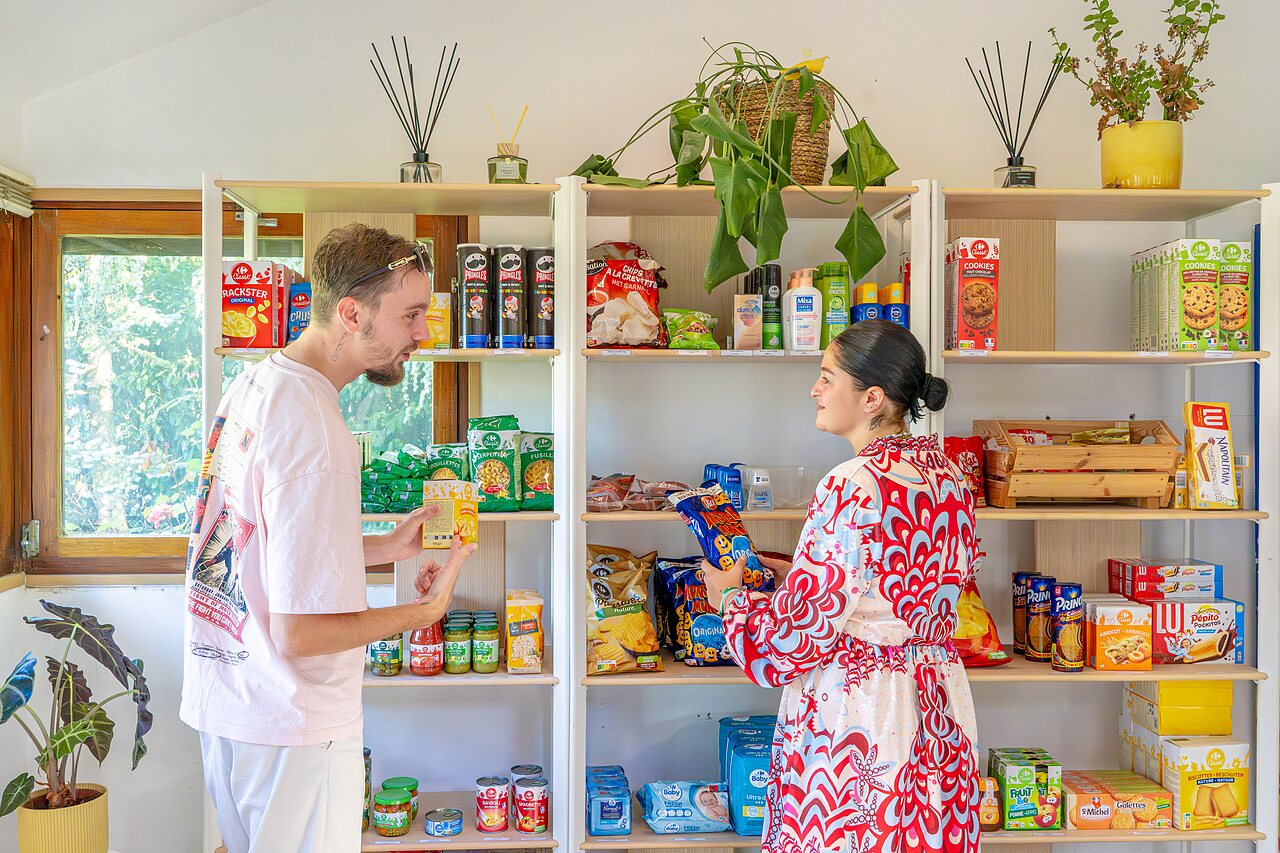 Pareja comprando en la tienda de comestibles del camping CAPFUN Parc de Paris, Villevaud� (77).