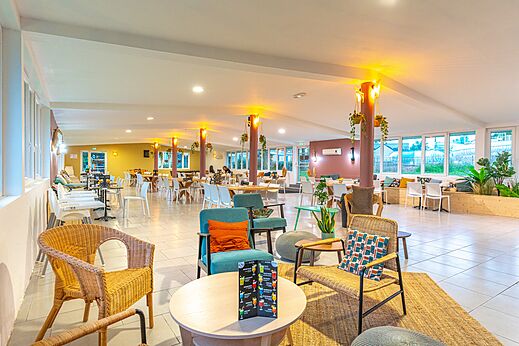 Zona de bar y restaurante moderna con mesas y sillas en el camping CAPFUN Parc de Paris en Villevaudé (77).