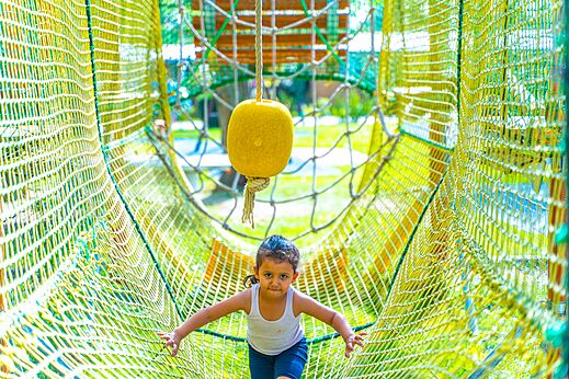 Niño en túnel de red del área de juegos en el camping CAPFUN Parc de Paris en Villevaudé.