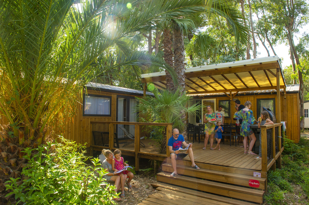 Familia relajada frente a Mobil-home moderno con terraza en el camping CAPFUN Parc et Plage en Hy�res les Palmiers.