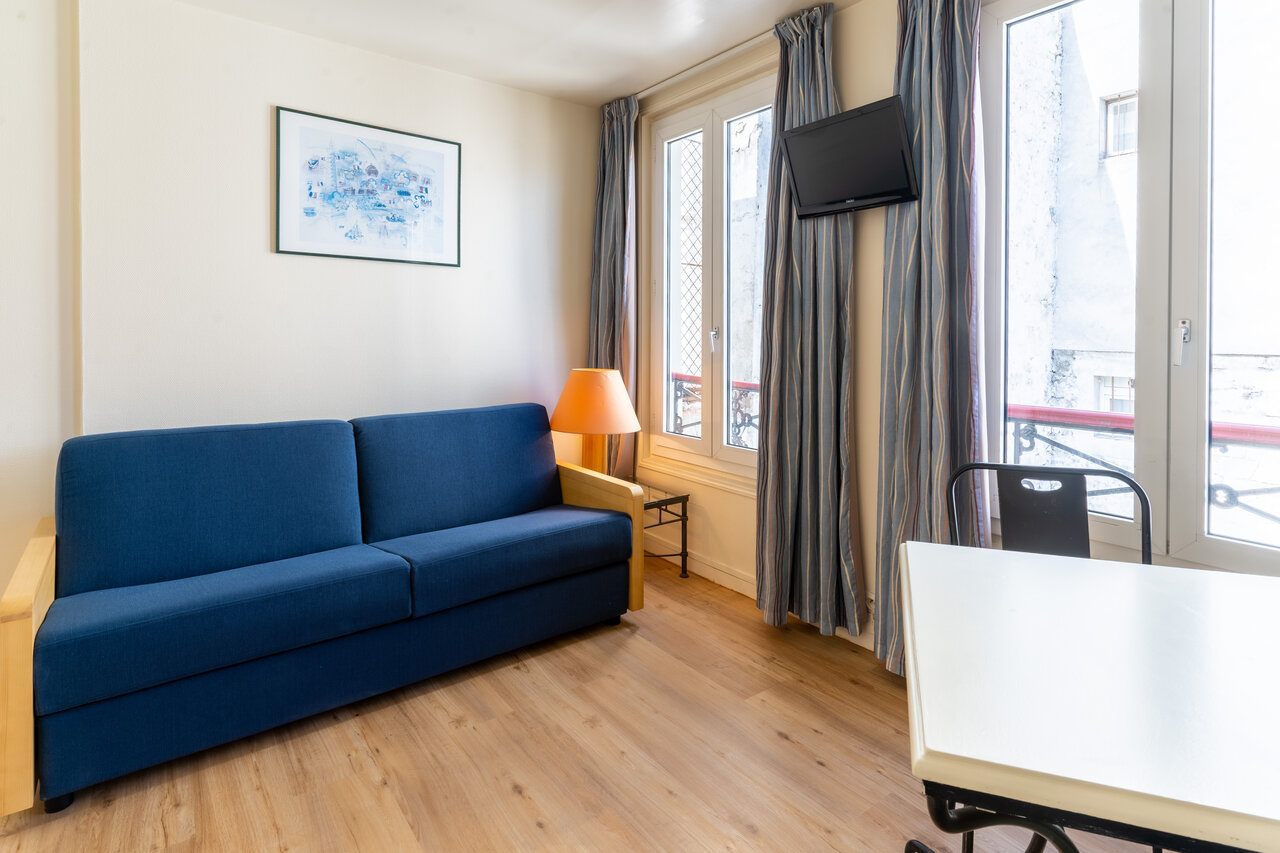 Sof� cama, TV de pared y zona de comedor en alojamiento en el camping CAPFUN Hotel Paris Saint Germain en PAR�S (75).