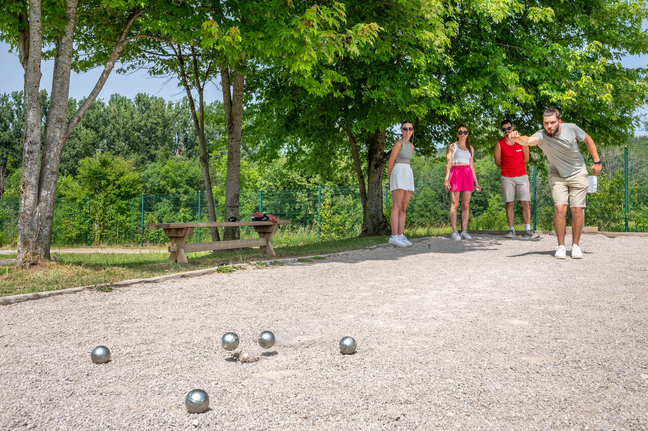 Cancha de petanca sombreada con veraneantes jugando, en el camping CAPFUN Pergola en Marigny (39).