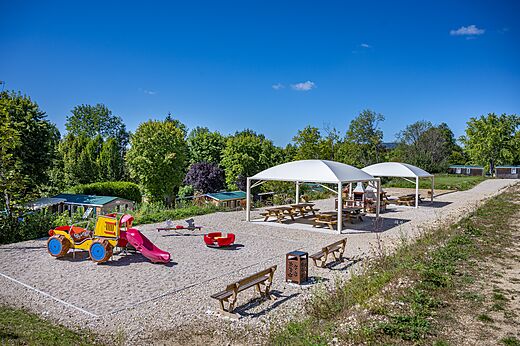 Zona de juegos colorida con tobogán y columpio en el camping CAPFUN Pergola en Marigny (39).