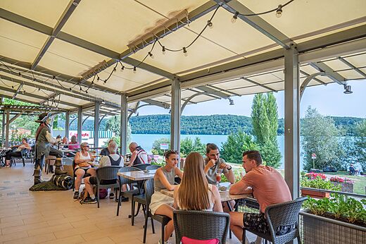 Restaurante con terraza y lago en camping CAPFUN Pergola en Marigny.