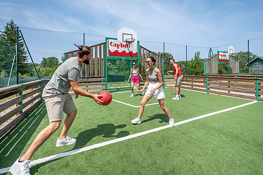 Familia jugando baloncesto en la cancha multideporte del camping CAPFUN Pergola en Marigny (39).