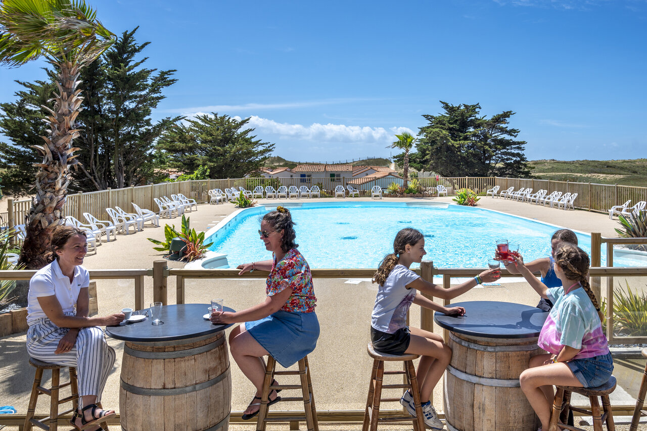 Familias disfrutando del bar de la piscina exterior en el camping CLICOCHIC Petit Bec en St Hilaire de Riez (85).