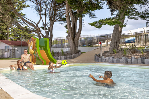 Familia jugando en piscina infantil con tobogán mono en camping CLICOCHIC Petit Bec en St Hilaire de Riez (85).