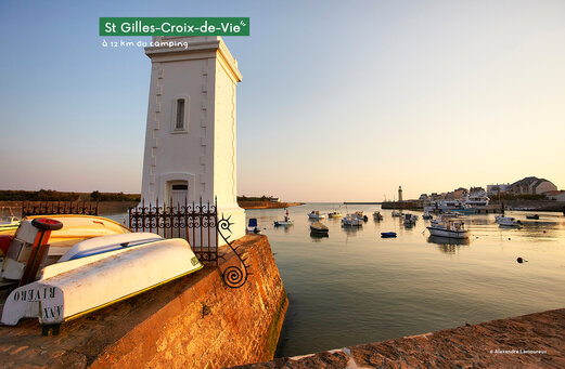 Puerto de Saint-Gilles-Croix-de-Vie con barcos y faro al atardecer.