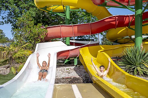 Ni�os felices en toboganes acu�ticos coloridos en el camping CAPFUN Pin�da en CAZAUX (33).