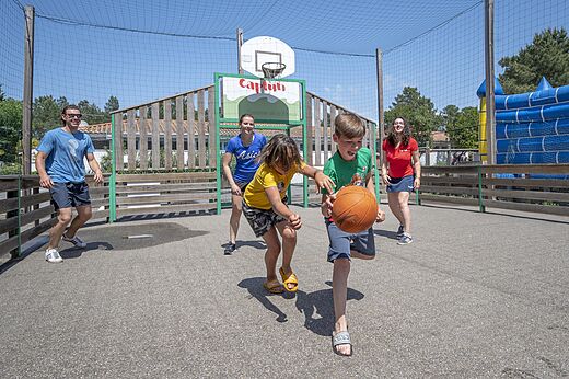 Cancha multideporte con niños jugando baloncesto en el camping CAPFUN Pinèda en CAZAUX (33).
