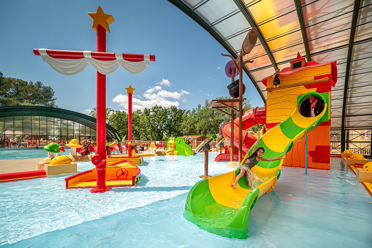 Ni�a en tobog�n acu�tico colorido, juegos de agua en el camping CAPFUN Pin�des du Luberon en PERTUIS (84).