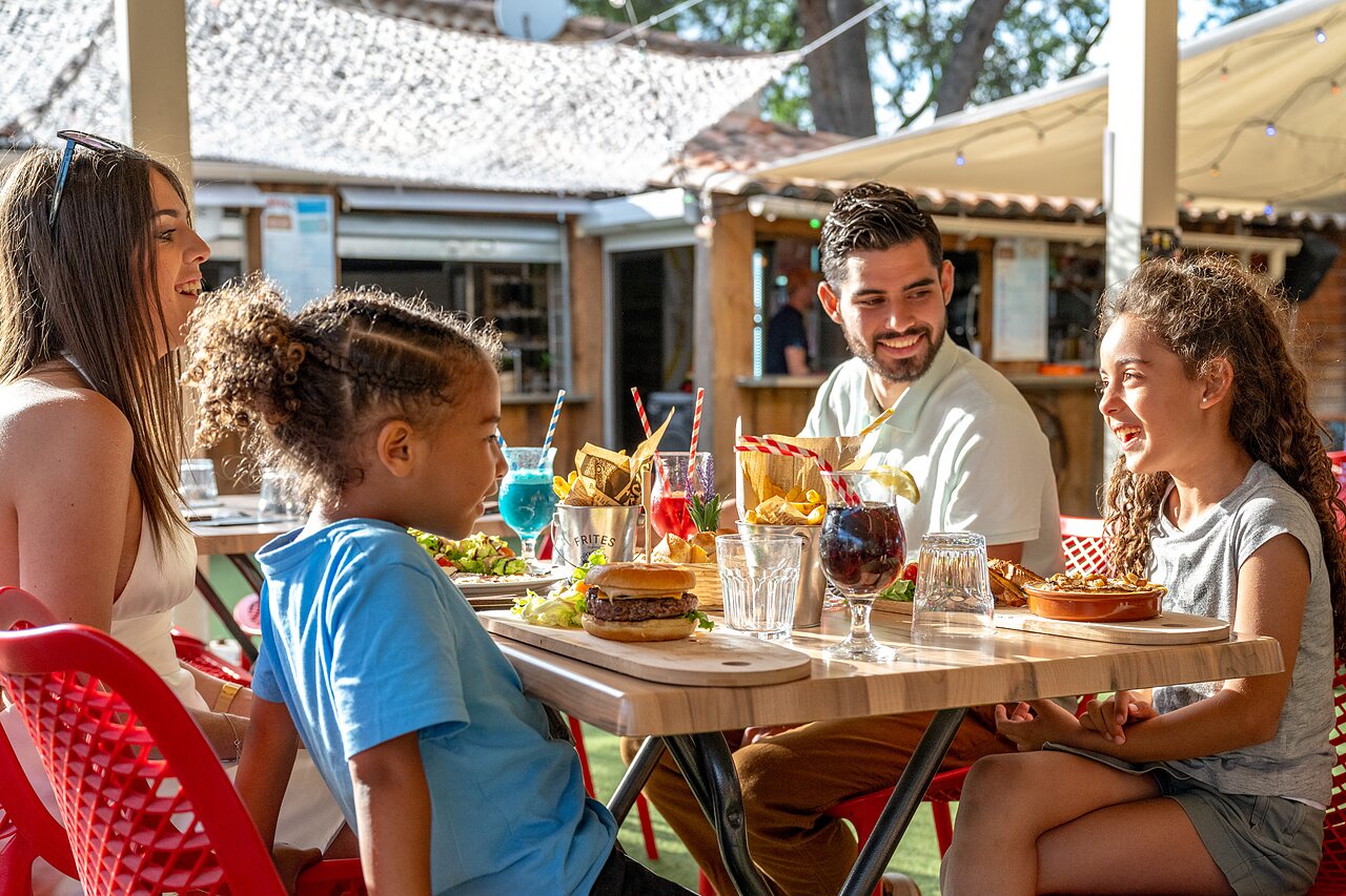 Familia sonriente almorzando en el restaurante del camping CAPFUN Pin�des du Luberon en PERTUIS (84).