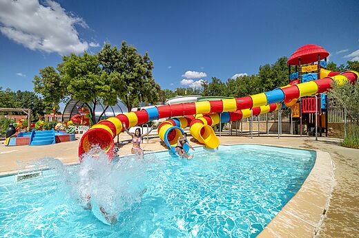 Toboganes acuáticos coloridos y piscina exterior camping CAPFUN Pinèdes du Luberon, PERTUIS (84).