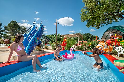 Niños y joven mujer jugando en piscina lúdica con tobogán en el camping CAPFUN Pinèdes del Luberon en PERTUIS (84).