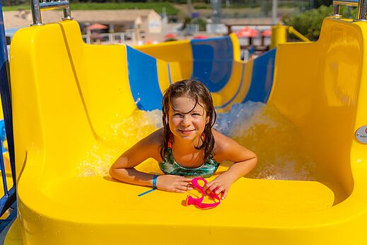 Niña sonriente en tobogán acuático en el camping CAPFUN La Pinède de Grimaud (83).