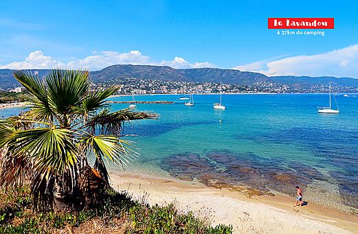 Playa de arena y mar turquesa con veleros en Le Lavandou, Costa Azul.