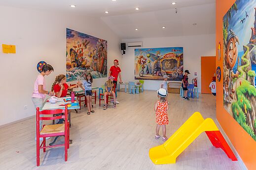 Club infantil con actividades y pequeño tobogán en el camping CAPFUN La Pinède de Grimaud.