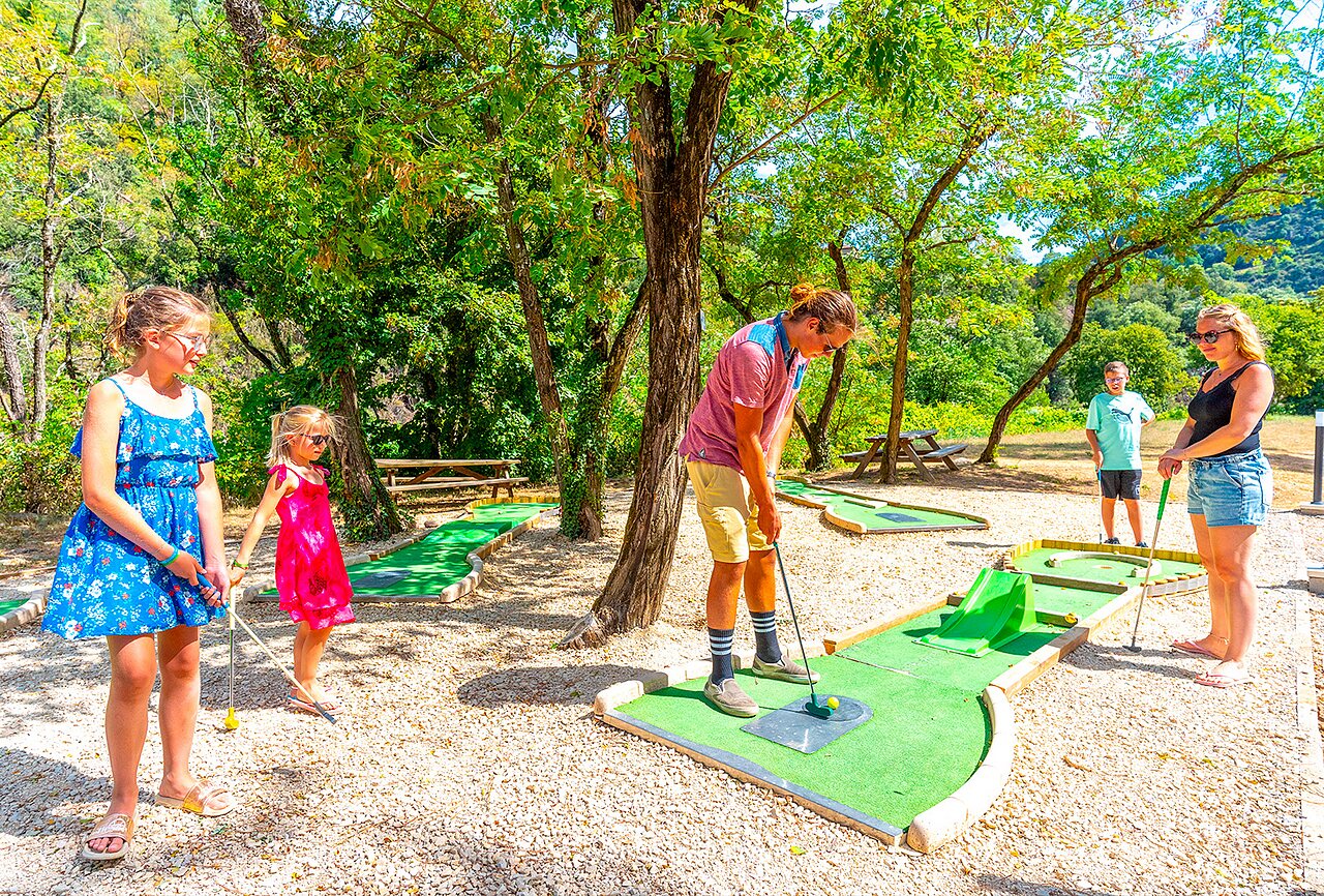 Familia jugando minigolf en campo sombreado en camping CAPFUN Plantas en SAINT VINCENT DE DURFORT (07).