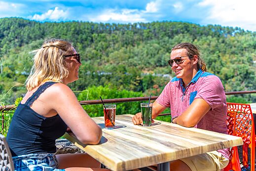 Pareja sonriente tomando bebidas en terraza, CAPFUN Plantas, SAINT VINCENT DE DURFORT (07).
