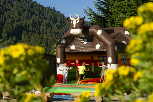 Niños divirtiéndose en juego inflable de vaca en camping CAPFUN Plan du Fernuy.