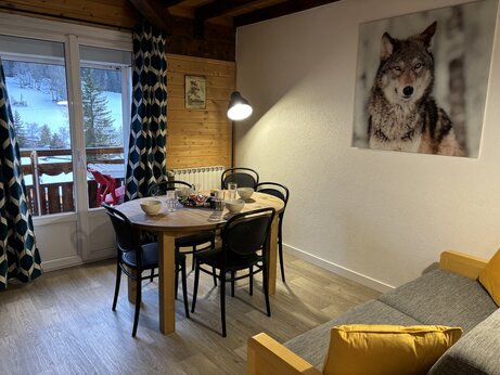Interior de Mobil-home con mesa de comedor y vista a la montaña nevada en el camping CAPFUN Plan du Fernuy en LA CLUSAZ (74).