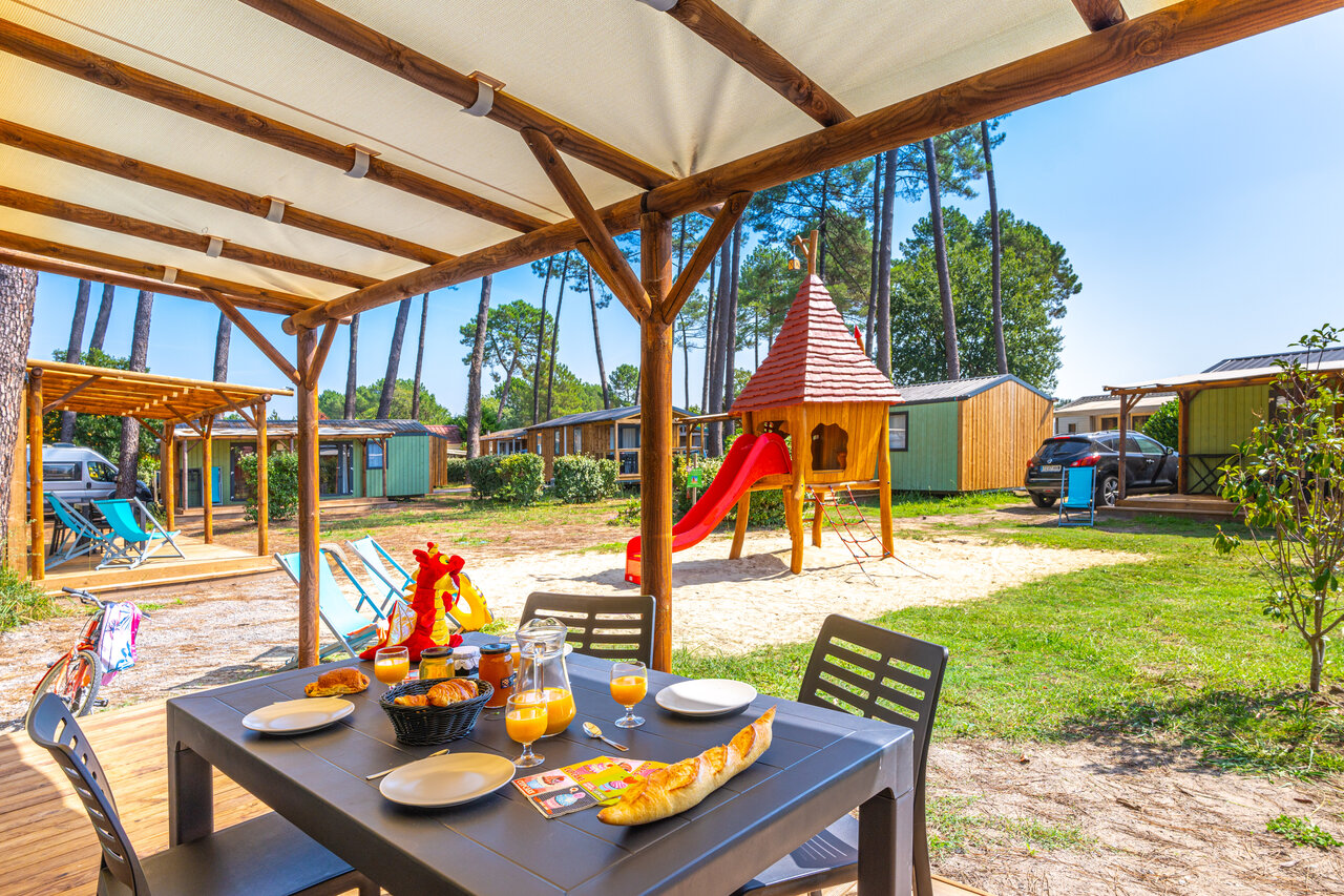 Desayuno en terraza de Mobil-home con zona de juegos infantiles en el camping CAPFUN Pomme de Pin en Saubion (40).