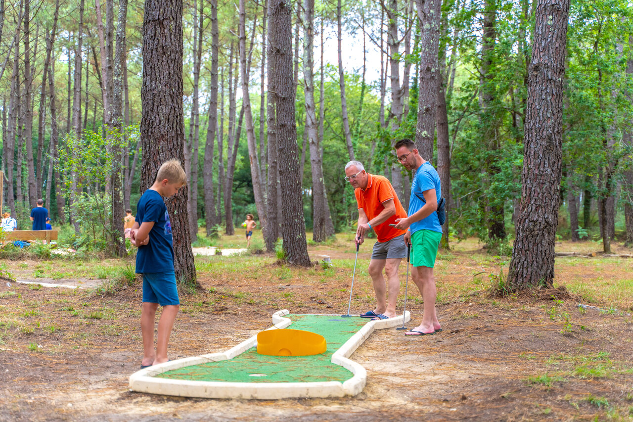 Familia jugando minigolf en bosque, camping CAPFUN Pomme de Pin en Saubion (40).