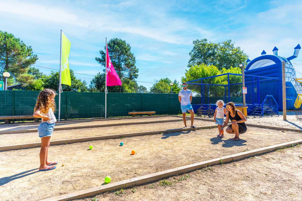 Familia jugando a la petanca en cancha dedicada en camping CAPFUN Pomme de Pin en Saubion (40).