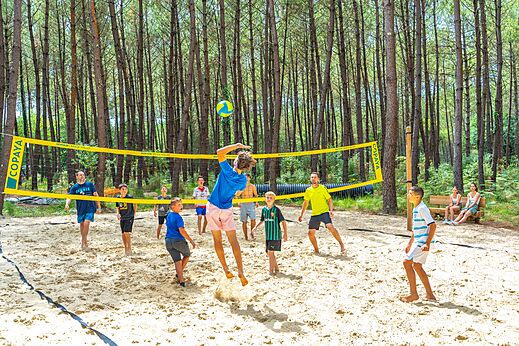 Cancha de voleibol de playa con jugadores en el camping CAPFUN Pomme de Pin en Saubion (40).