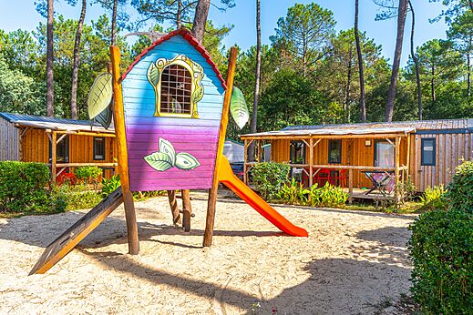 Zona de juegos colorida con tobog�n y Mobil-homes en el camping CAPFUN Pomme de Pin en Saubion (40).