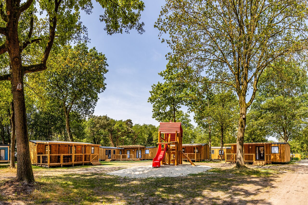 Mobil-homes de madera y parque infantil con tobog�n en el camping CAPFUN Ponderosa en Ulicoten.