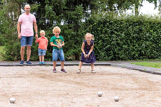 Familia jugando a la petanca en la cancha del camping CAPFUN Ponderosa en Ulicoten.