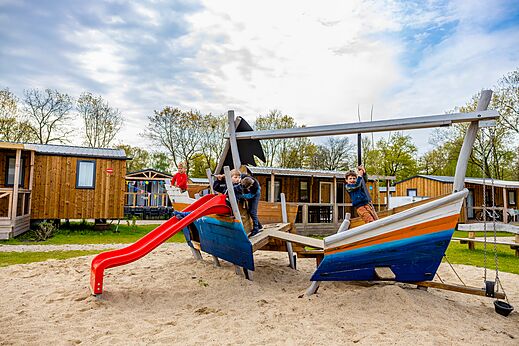 Zona de juegos barco, tobogán y niños en el camping CAPFUN Ponderosa en Ulicoten.